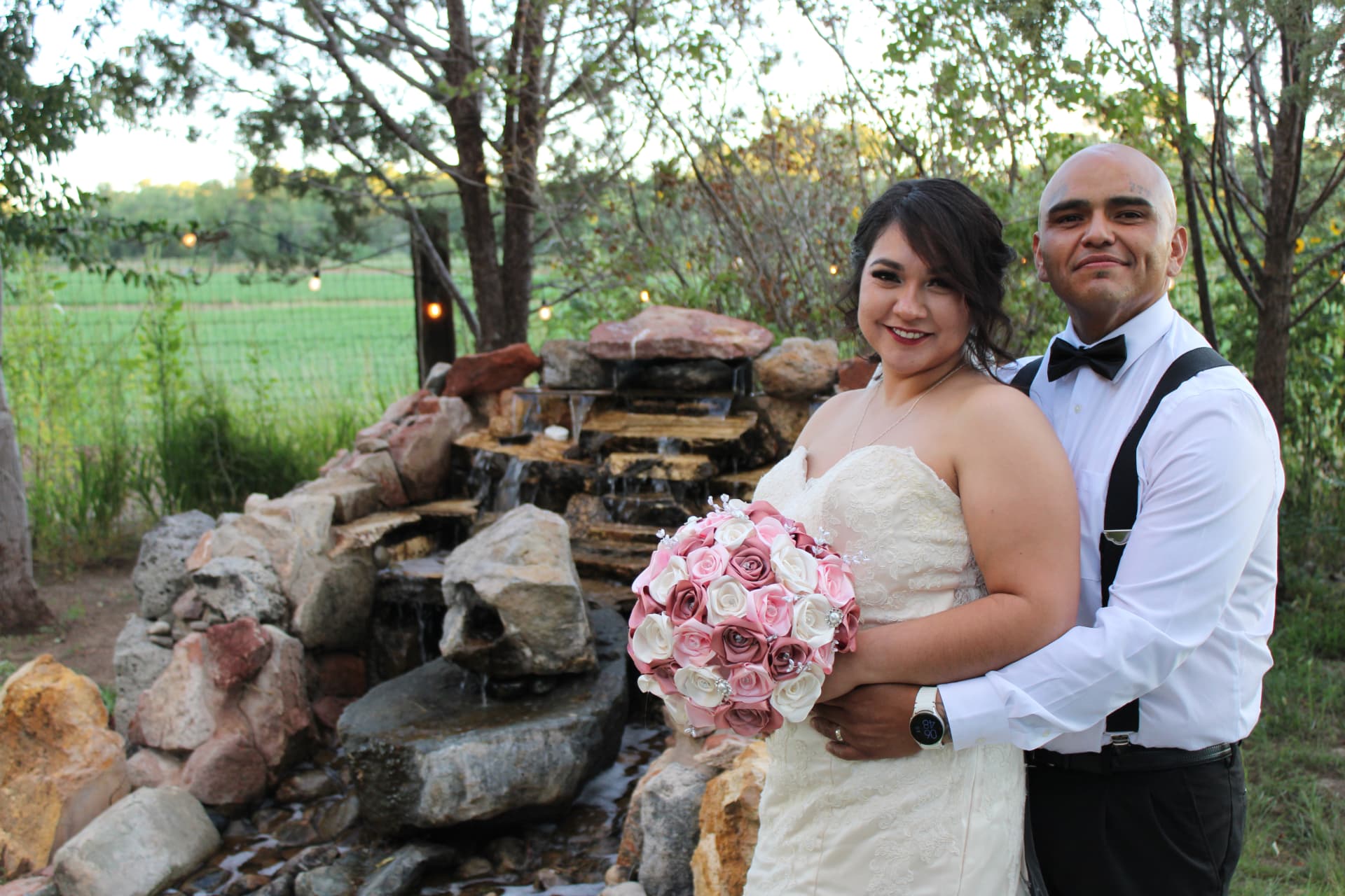 Wedding couple beside an outdoor rock waterfall